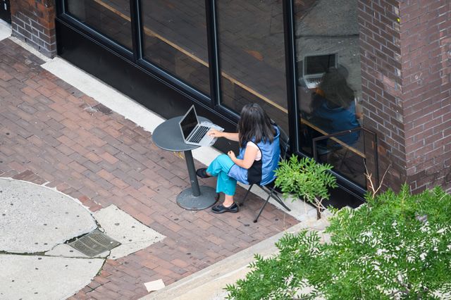 A person works on her laptop outside a restaurant in Kips Bay, July 11, 2020